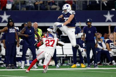 ARLINGTON, TEXAS - NOVEMBER 24: Jake Ferguson #87 of the Dallas Cowboys jumps over Jason Pinnock #27 of the New York Giants during the second half at AT&T Stadium on November 24, 2022 in Arlington, Texas.   Wesley Hitt/Getty Images/AFP (Photo by Wesley Hitt / GETTY IMAGES NORTH AMERICA / Getty Images via AFP)<!-- NICAID(15281021) -->