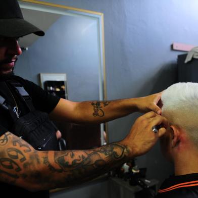 CAXIAS DO SUL, RS, BRASIL, 21/12/2022. Com a chegada do verão, platinar os cabelos é tendência entre jovens e adultos. As barbearias trabalham com a agenda apertada para dar conta de tantos pedidos em uma mesma época. Influenciados por jogadores de futebol, platinar os cabelos têm sido a tendência entre jovens, crianças e até adultos. (Porthus Junior/Agência RBS)<!-- NICAID(15302620) -->