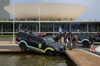 Members of the Federal Legislative Police stand next a vehicle that crashed into a fountain as supporters of Brazilian former President Jair Bolsonaro invade the National Congress in Brasilia on January 8, 2023. - Hundreds of supporters of Brazils far-right ex-president Jair Bolsonaro broke through police barricades and stormed into Congress, the presidential palace and the Supreme Court Sunday, in a dramatic protest against President Luiz Inacio Lula da Silvas inauguration last week. (Photo by Sergio Lima / AFP)Editoria: WARLocal: BrasíliaIndexador: SERGIO LIMASecao: demonstrationFonte: AFPFotógrafo: STR<!-- NICAID(15315496) -->