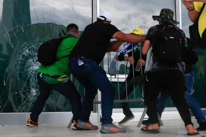 Supporters of Brazilian former President Jair Bolsonaro break a window as they invade Planalto Presidential Palace in Brasilia on January 8, 2023. - Hundreds of supporters of Brazils far-right ex-president Jair Bolsonaro broke through police barricades and stormed into Congress, the presidential palace and the Supreme Court Sunday, in a dramatic protest against President Luiz Inacio Lula da Silvas inauguration last week. (Photo by Sergio Lima / AFP)Editoria: WARLocal: BrasíliaIndexador: SERGIO LIMASecao: demonstrationFonte: AFPFotógrafo: STR<!-- NICAID(15315540) -->