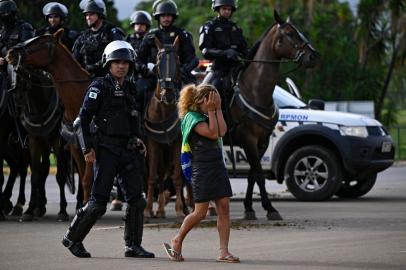 A demonstrator is escorted away as a camp by supporters of Brazils far-right ex-president Jair Bolsonaro that had been set up in front of the Army headquarters in Brasilia, is being dismantled on January 9, 2023, a day after backers of the ex-president invaded the Congress, presidential palace and Supreme Court. - Brazilian security forces locked down the area around Congress, the presidential palace and the Supreme Court Monday, a day after supporters of ex-president Jair Bolsonaro stormed the seat of power in riots that triggered an international outcry. Hardline Bolsonaro supporters have been protesting outside army bases calling for a military intervention to stop Lula from taking power since his election win. (Photo by Mauro PIMENTEL / AFP)Editoria: WARLocal: BrasíliaIndexador: MAURO PIMENTELSecao: demonstrationFonte: AFPFotógrafo: STF<!-- NICAID(15315816) -->