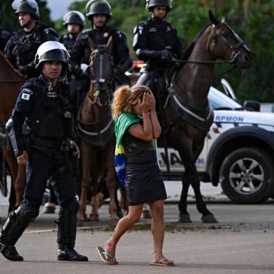 A demonstrator is escorted away as a camp by supporters of Brazils far-right ex-president Jair Bolsonaro that had been set up in front of the Army headquarters in Brasilia, is being dismantled on January 9, 2023, a day after backers of the ex-president invaded the Congress, presidential palace and Supreme Court. - Brazilian security forces locked down the area around Congress, the presidential palace and the Supreme Court Monday, a day after supporters of ex-president Jair Bolsonaro stormed the seat of power in riots that triggered an international outcry. Hardline Bolsonaro supporters have been protesting outside army bases calling for a military intervention to stop Lula from taking power since his election win. (Photo by Mauro PIMENTEL / AFP)Editoria: WARLocal: BrasíliaIndexador: MAURO PIMENTELSecao: demonstrationFonte: AFPFotógrafo: STF<!-- NICAID(15315816) -->