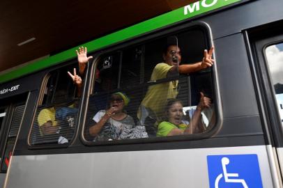 A small group of supporters of Brazils far-right ex-president Jair Bolsonaro who had been arrested after they invaded the Congress, presidential palace and Supreme Court, gesture from inside a bus while leaving the Federal Police headquarters in Brasilia, on January 10, 2023. - Brazilian security forces cleared protest camps on the eve and arrested 1,500 people as President Luiz Inacio Lula da Silva condemned acts of terrorism after a far-right mob stormed the seat of power, unleashing chaos on the capital. Hardline Bolsonaro supporters have been protesting outside army bases calling for a military intervention to stop Lula from taking power since his election win. (Photo by MAURO PIMENTEL / AFP)Editoria: WARLocal: BrasíliaIndexador: MAURO PIMENTELSecao: demonstrationFonte: AFPFotógrafo: STF<!-- NICAID(15317531) -->