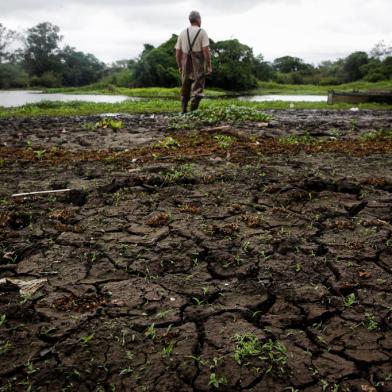 Gravataí, RS, Brasil, 28-12-2022: O servidor público aposentado Breno Duarte observa o rio Gravataí com nível abaixo do normal no Balneário Passo das Canoas. Seca do Rio Gravataí afeta Região Metropolitana de Porto Alegre. Foto: Mateus Bruxel / Agência RBSIndexador: Mateus Bruxel<!-- NICAID(15306736) -->