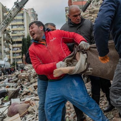 A rescuer reacts as he carries a body found in the rubble in Adana on February 6, 2023, after a 7.8-magnitude earthquake struck the countrys south-east. - The combined death toll has risen to over 1,900 for Turkey and Syria after the regions strongest quake in nearly a century on February 6, 2023. Turkeys emergency services said at least 1,121 people died in the 7.8-magnitude earthquake, with another 783 confirmed fatalities in Syria, putting that toll at 1,904. (Photo by Can EROK / AFP)Editoria: DISLocal: AdanaIndexador: CAN EROKSecao: earthquakeFonte: AFPFotógrafo: STR<!-- NICAID(15341349) -->