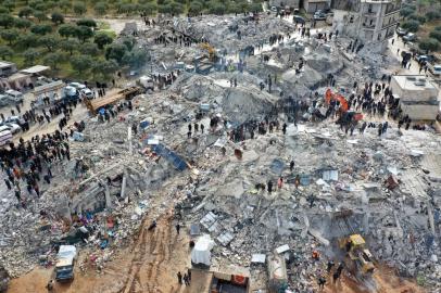 This aerial view shows residents searching for victims and survivors amidst the rubble of collapsed buildings following an earthquake in the village of Besnia near the twon of Harim, in Syrias rebel-held noryhwestern Idlib province on the border with Turkey, on February 6, 2022. - Hundreds have been reportedly killed in north Syria after a 7.8-magnitude earthquake that originated in Turkey and was felt across neighbouring countries. (Photo by Omar HAJ KADOUR / AFP)<!-- NICAID(15342190) -->