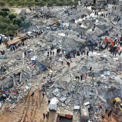 This aerial view shows residents searching for victims and survivors amidst the rubble of collapsed buildings following an earthquake in the village of Besnia near the twon of Harim, in Syrias rebel-held noryhwestern Idlib province on the border with Turkey, on February 6, 2022. - Hundreds have been reportedly killed in north Syria after a 7.8-magnitude earthquake that originated in Turkey and was felt across neighbouring countries. (Photo by Omar HAJ KADOUR / AFP)<!-- NICAID(15342190) -->