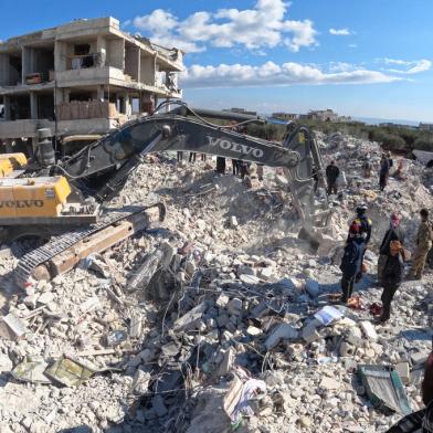 Rescue workers look for survivors amid the rubble of a building in the rebel-held town of Jindayris on February 10, 2023, days after an earthquake hit Turkey and Syria. - The 7.8-magnitude quake early on February 6 has killed more than 20,000 people in Turkey and war-ravaged Syria, according to officials and medics in the two countries, flattening entire neighbourhoods. (Photo by Rami al SAYED / AFP)<!-- NICAID(15345640) -->