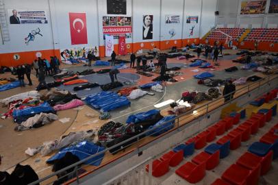 People walk past the bodies of victims stored at the citys sports hall, two days after a strong earthquake struck the region, in the southeastern Turkish city of Kahramanmaras on February 8, 2023. - Many have taken refuge from relentless aftershocks, cold rain and snow in mosques, schools and even bus shelters -- burning debris to try to stay warm, after the earthquake, which is the largest Turkey had seen since 1939. (Photo by OZAN KOSE / AFP)<!-- NICAID(15347066) -->